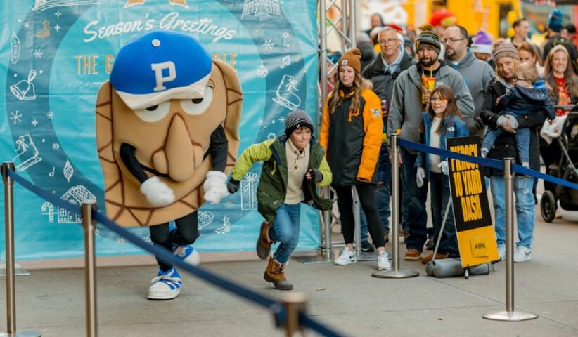 A perogie racing a child while a crowd watches