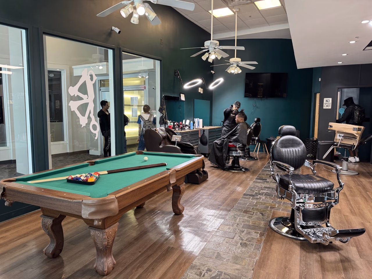 An interior shot of BONEZ barbershop where there is a pool table and a patron getting their hair cut.