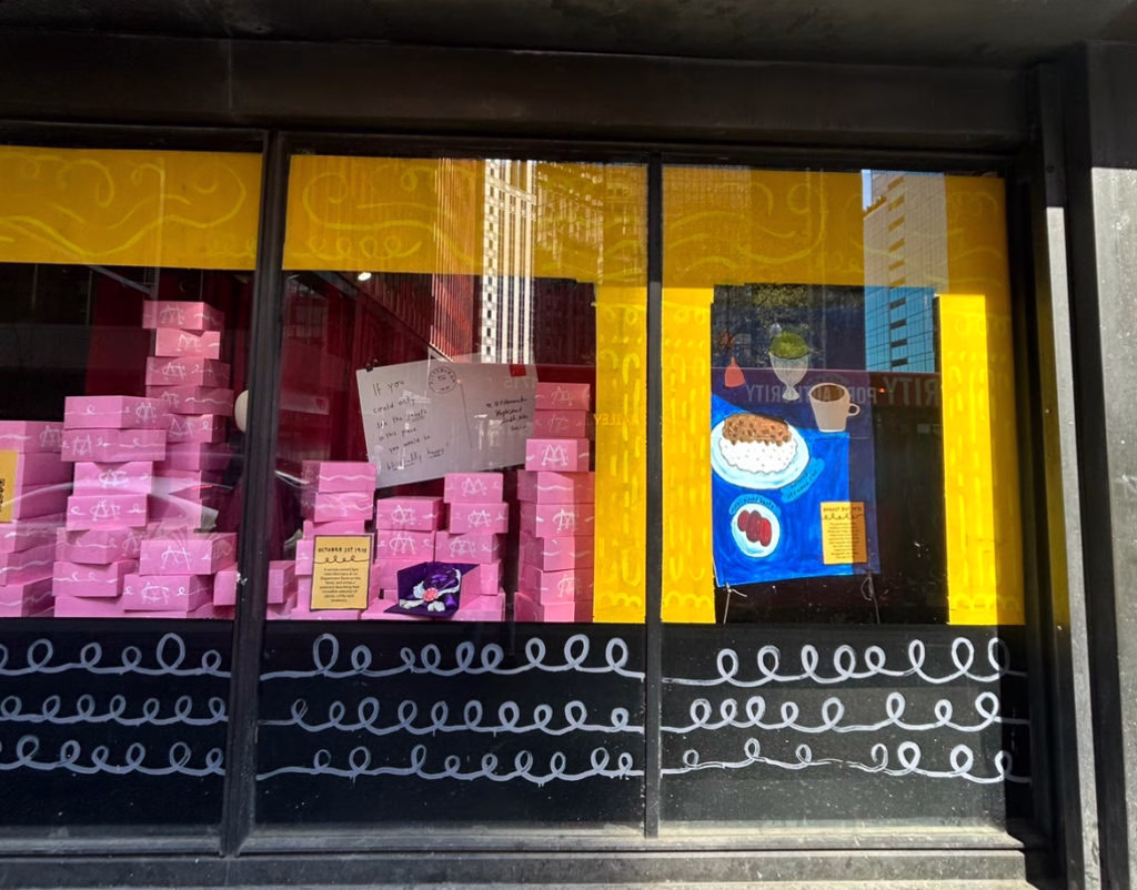The outside windows of a business presenting pink boxes of product.