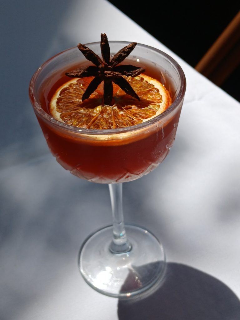 Pizzaiolo Primo, Signature Cocktail, "The Runway."  Made with Rye whiskey, Aperol, wild blueberry amaro, lemon, and garnished with a dehydrated orange and star anise
