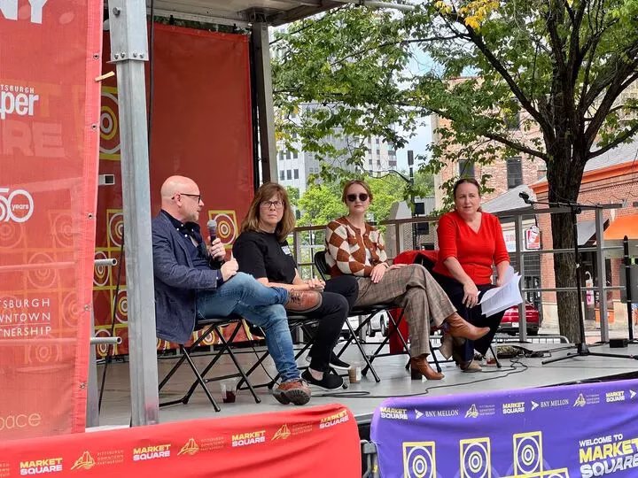A panel of people sit on a stage