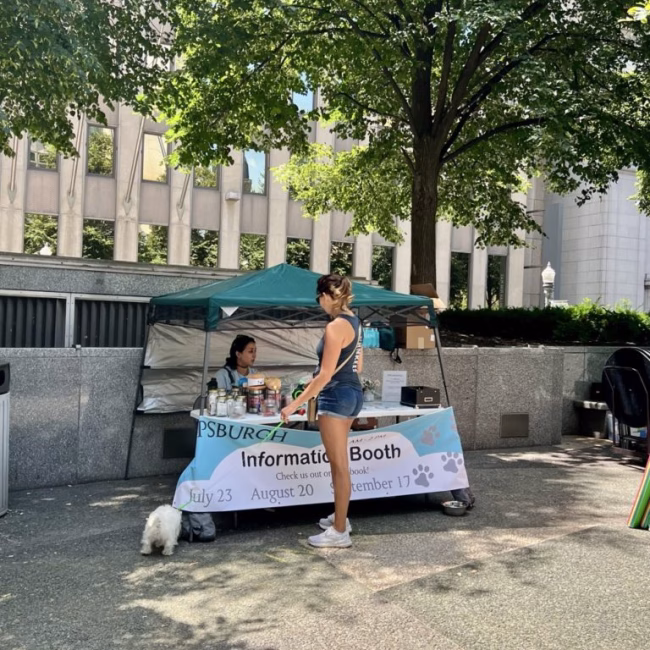A woman at an information booth with her dog.