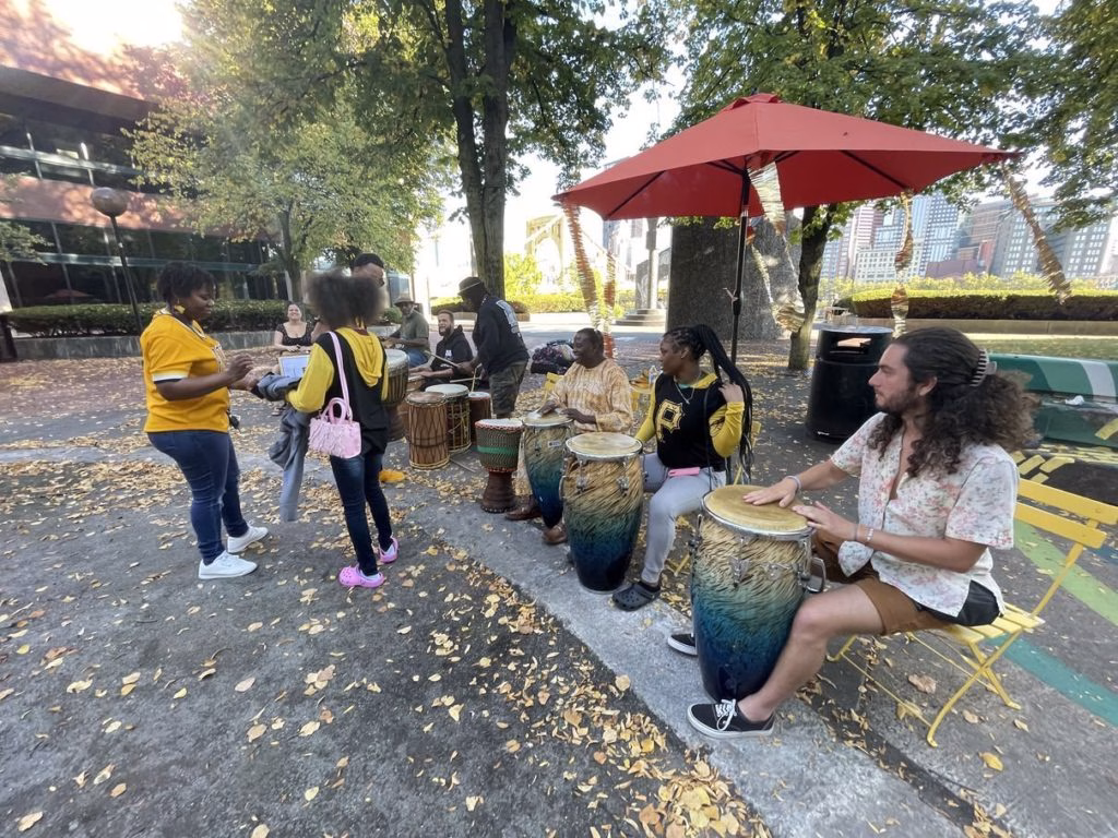 A group of people playing bongos outside.