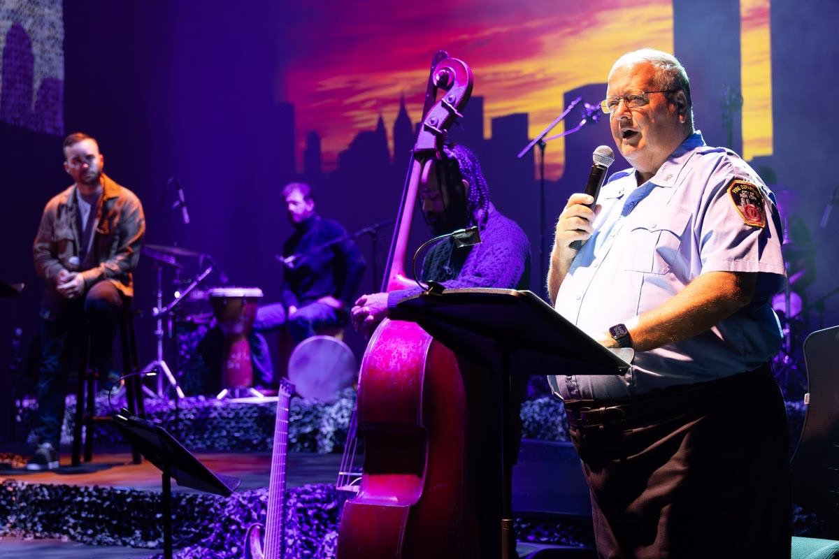 A man sings at a podium with a live jazz band behind him.