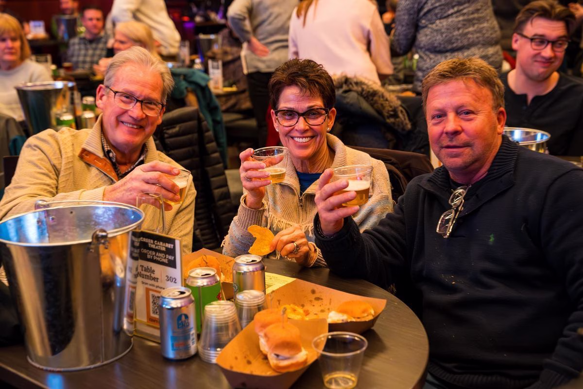 Three crowd members enjoying some food and beer.